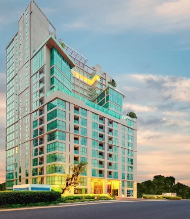 Modern glass-fronted building with a landscaped entrance under a cloudy sky.